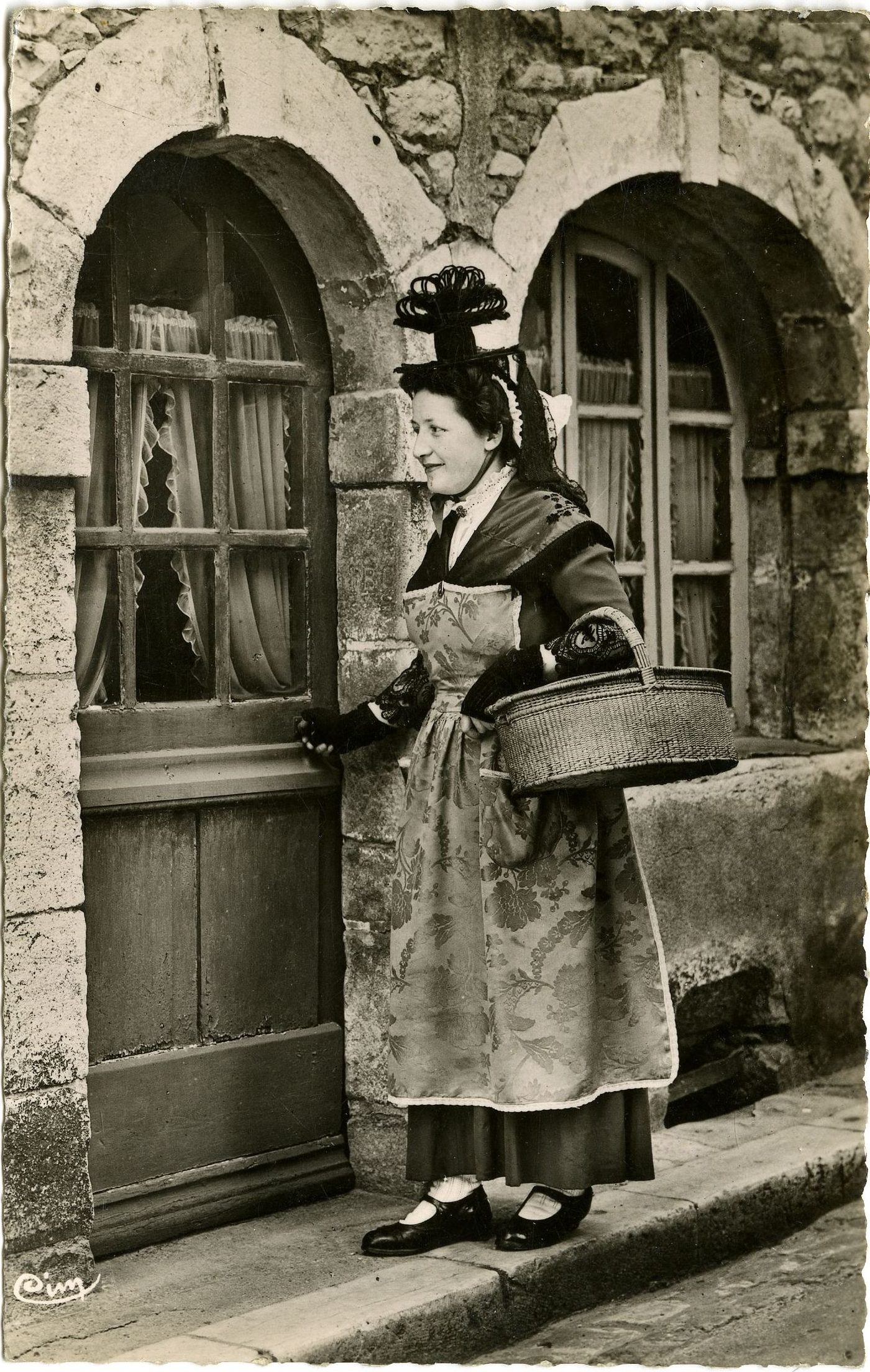 Groupe du costume tournugeois. Tournus. Retour du marché. Tournugeoise coiffée du Brelot, rive gauche, vêtue robe et tablier de soie brochée : panier à provisions à 2 couvercles dit bouchons.