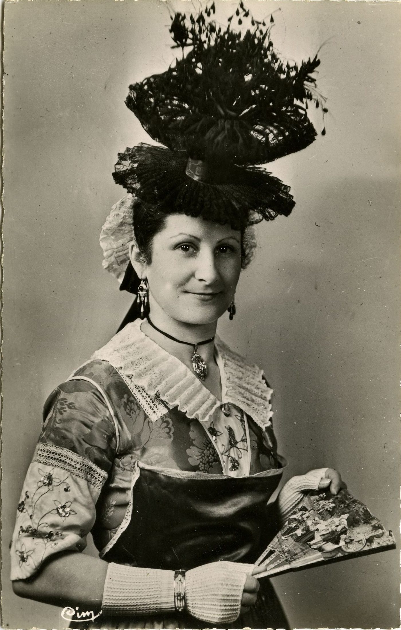 Tournus. Riche bourgeoise du tournugeois. Robe de soie brochée, couleur vive, avec plastron et manches ornées de paillettes d'or et d'argent. Riches bijoux. Bonnet emprisonnant le chignon. Chapeau noir dit Brelot.
